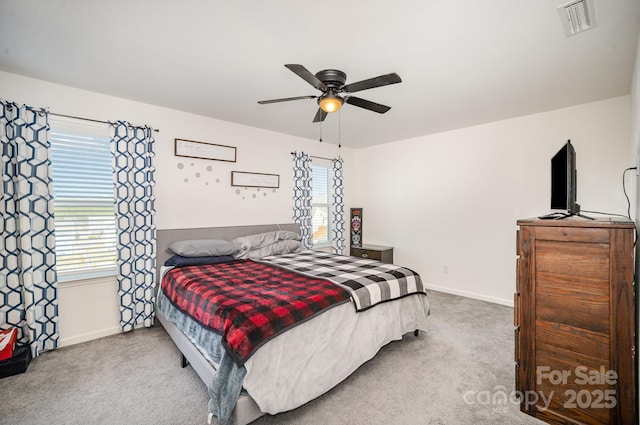 carpeted bedroom featuring visible vents, baseboards, and multiple windows