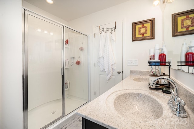 full bath featuring double vanity, a sink, and a shower stall