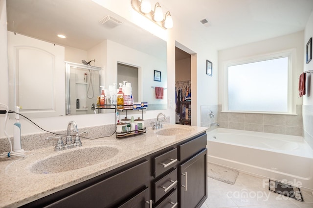 bathroom with double vanity, a spacious closet, a sink, and tile patterned floors