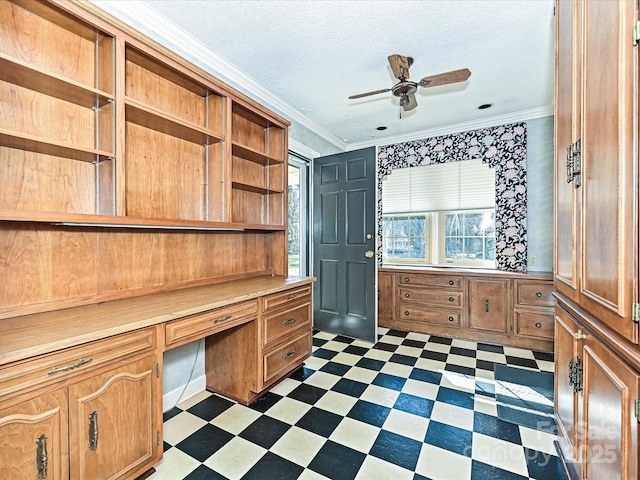 unfurnished office with a textured ceiling, dark floors, ornamental molding, and built in desk