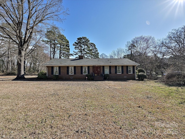 ranch-style house with brick siding, a front lawn, and a chimney