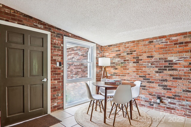 324 Old Leicester Hwy, Asheville, NC 28806 - dining space featuring brick wall, a textured ceiling, lofted ceiling, healthy amount of natural light, and light tile patterned floors