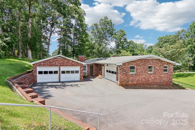 324 Old Leicester Hwy, Asheville, NC 28806 - view of front of home featuring a chimney, brick siding, a front lawn, a garage, and view of scattered trees