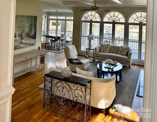 living area featuring beamed ceiling, wood finished floors, coffered ceiling, and ceiling fan