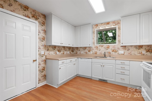 kitchen with a sink, white appliances, light wood-style flooring, wallpapered walls, and visible vents
