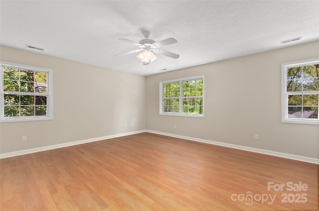 unfurnished room with ceiling fan, visible vents, and plenty of natural light