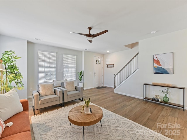 living area featuring wood finished floors, visible vents, baseboards, and stairs