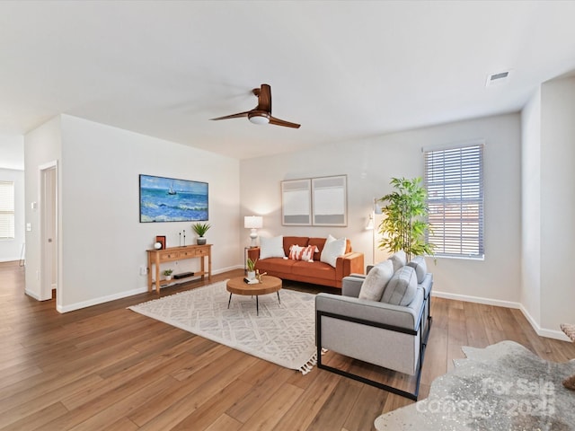 living area with a ceiling fan, baseboards, and wood finished floors