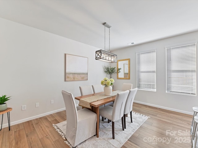 dining space with light wood-type flooring, visible vents, and baseboards