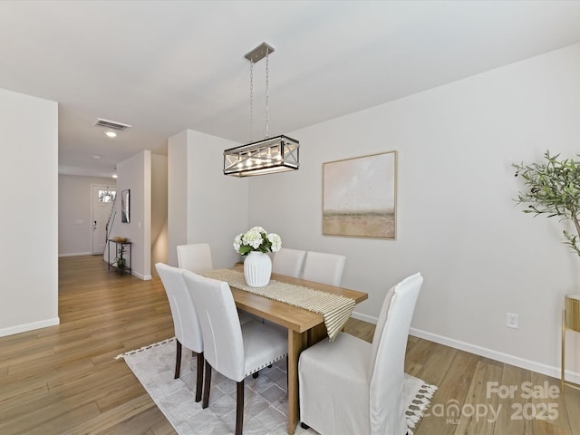 dining area with baseboards, visible vents, and wood finished floors