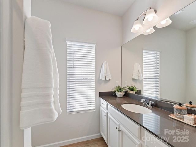 bathroom with a notable chandelier, vanity, a wealth of natural light, and baseboards