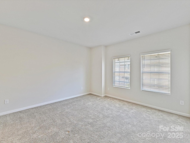 unfurnished room with light carpet, visible vents, and baseboards