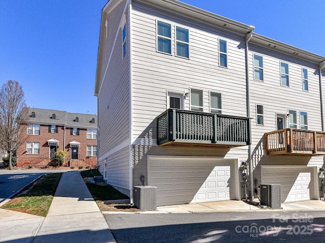 rear view of property featuring a garage, central AC, and a balcony