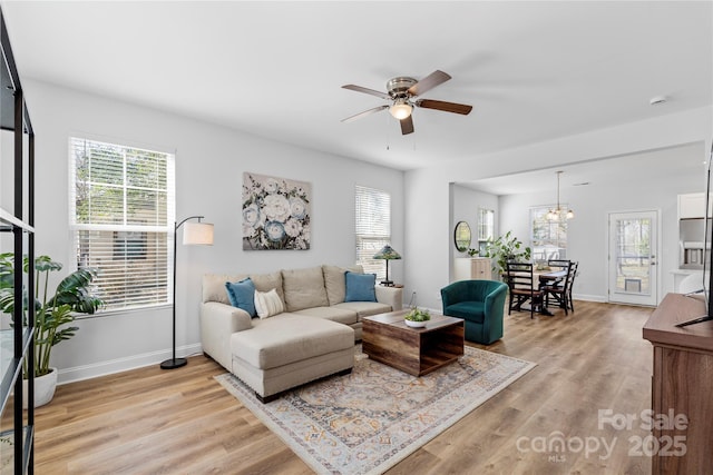 living room featuring baseboards, a healthy amount of sunlight, and light wood finished floors