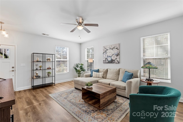 living room featuring ceiling fan, wood finished floors, visible vents, and baseboards