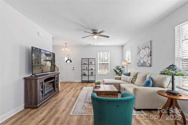 living area featuring a healthy amount of sunlight, light wood-style flooring, baseboards, and a ceiling fan