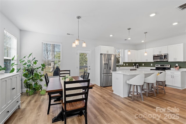 kitchen featuring stainless steel appliances, hanging light fixtures, light countertops, and white cabinetry