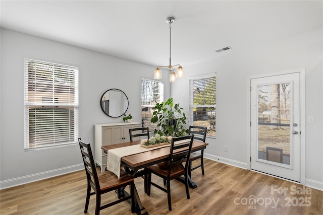 dining area featuring light wood-style floors, baseboards, visible vents, and an inviting chandelier