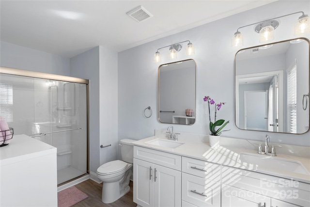 bathroom with a stall shower, a sink, and visible vents