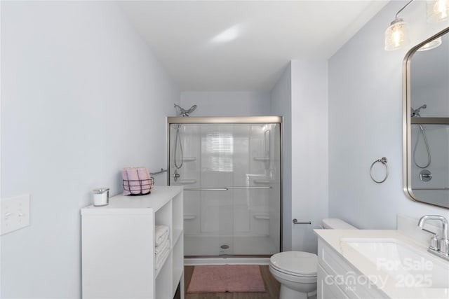 bathroom with toilet, a shower stall, and vanity