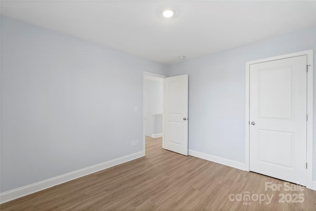 unfurnished bedroom with wood finished floors and baseboards