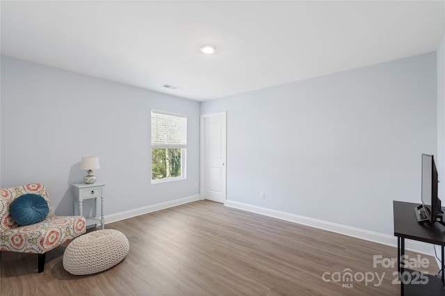 living area with visible vents, baseboards, and wood finished floors