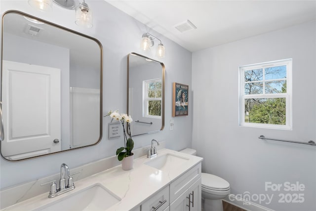 bathroom featuring visible vents, a sink, toilet, and double vanity