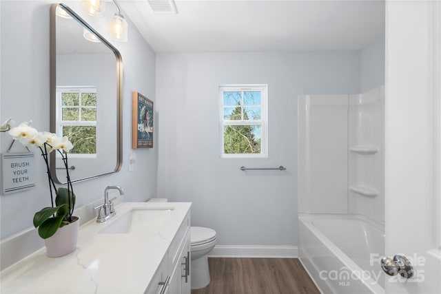 bathroom featuring visible vents, baseboards, toilet, wood finished floors, and vanity