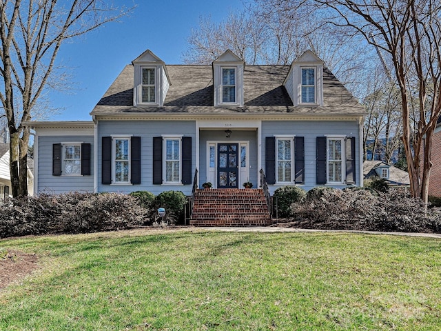 cape cod-style house with a shingled roof and a front yard