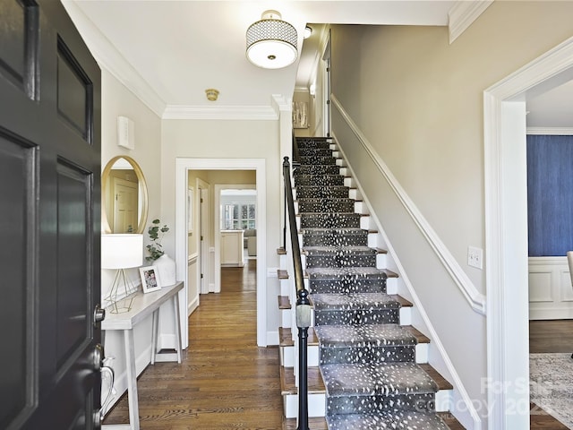 staircase with crown molding and wood finished floors