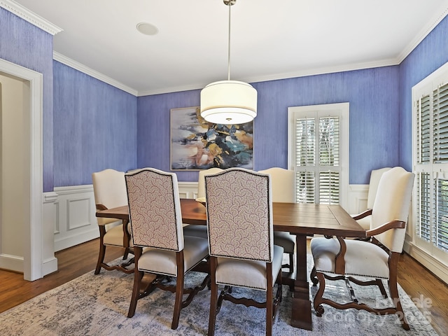 dining room with dark wood-style floors, ornamental molding, and a wainscoted wall