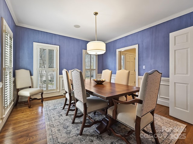 dining room featuring dark wood-style floors, ornamental molding, and wainscoting