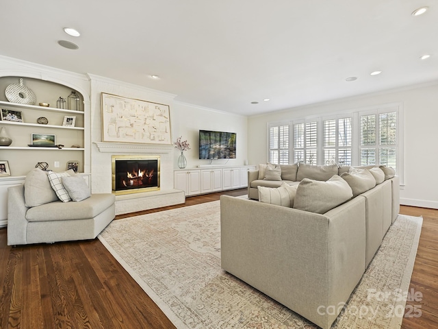 living room featuring ornamental molding, a glass covered fireplace, dark wood finished floors, and recessed lighting