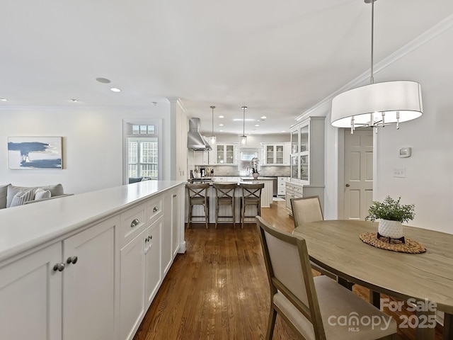 dining area with dark wood-style flooring, crown molding, and recessed lighting