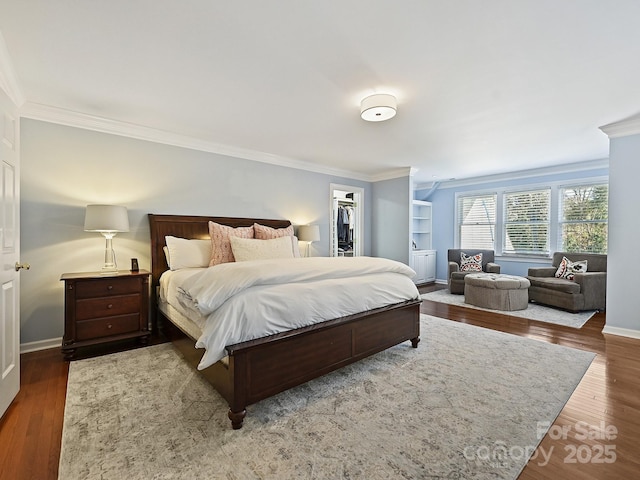 bedroom featuring ornamental molding, dark wood-style flooring, a spacious closet, and baseboards