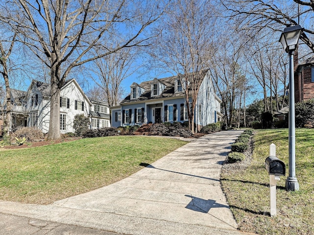 cape cod home with driveway, a front lawn, and a residential view