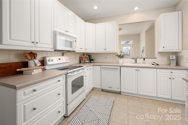 kitchen featuring a sink, white appliances, and white cabinets