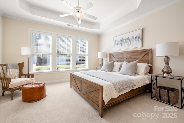 carpeted bedroom with a tray ceiling, visible vents, ornamental molding, and a ceiling fan