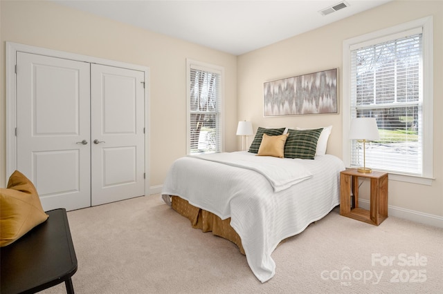 bedroom with visible vents, light carpet, baseboards, and a closet