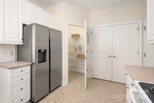 kitchen featuring white electric range, tasteful backsplash, white cabinetry, stainless steel fridge with ice dispenser, and light tile patterned floors