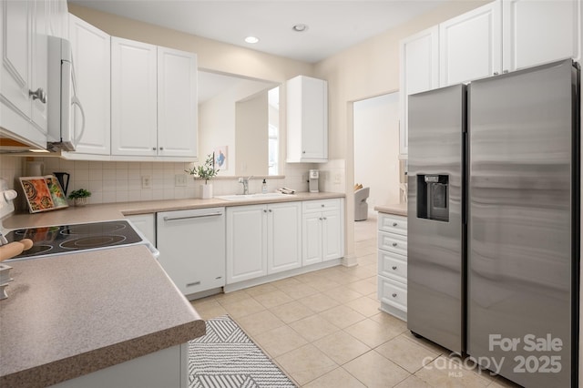 kitchen with light tile patterned floors, decorative backsplash, white cabinets, white appliances, and a sink