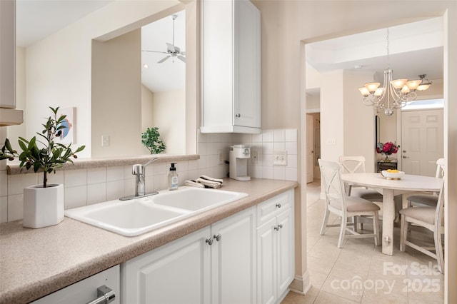 kitchen with a sink, decorative backsplash, white cabinets, and light countertops