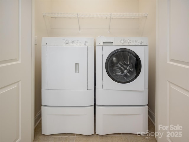 clothes washing area with washer and dryer, laundry area, and light tile patterned floors