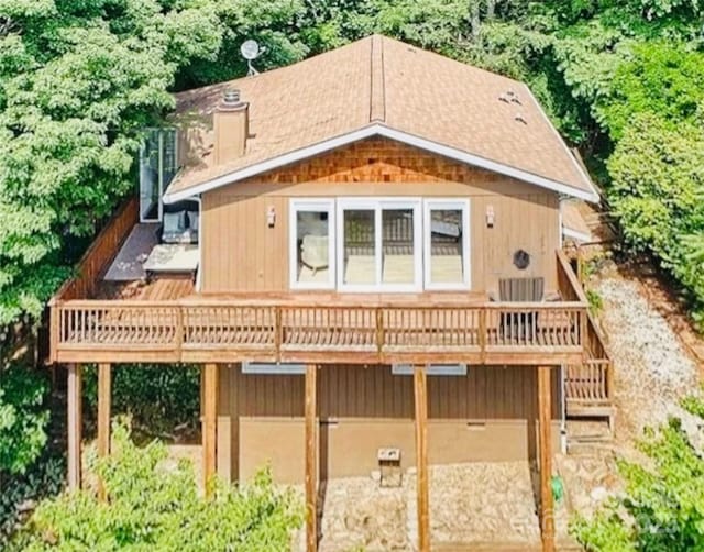 back of property featuring driveway, stairs, a chimney, and a wooden deck