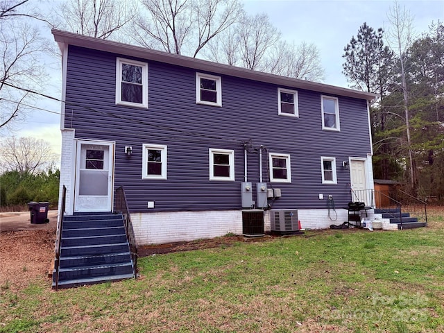 back of property with central AC unit and a yard