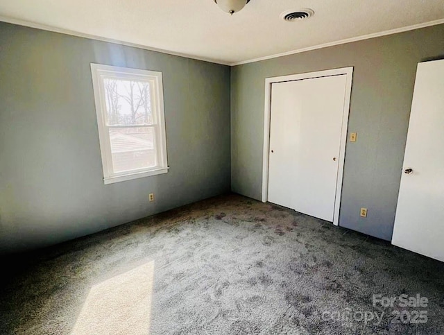 unfurnished bedroom featuring ornamental molding and dark carpet