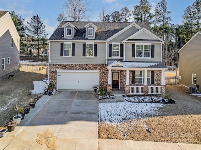 craftsman house with brick siding, a porch, central AC unit, a garage, and driveway