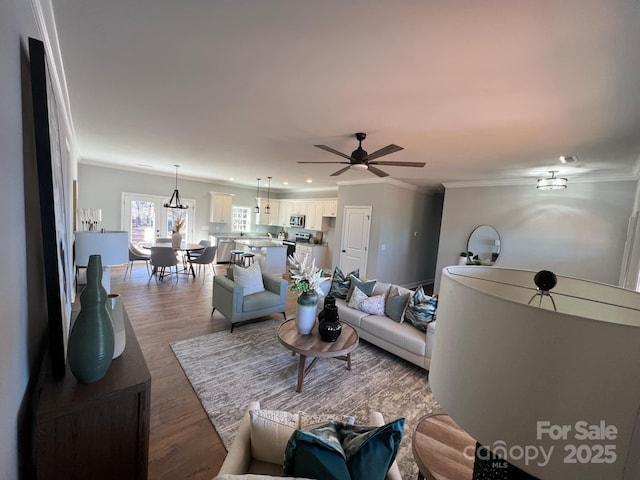 living room with ceiling fan, wood finished floors, visible vents, and crown molding