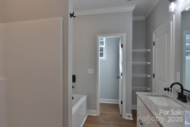 bathroom with crown molding, a washtub, wood finished floors, and vanity