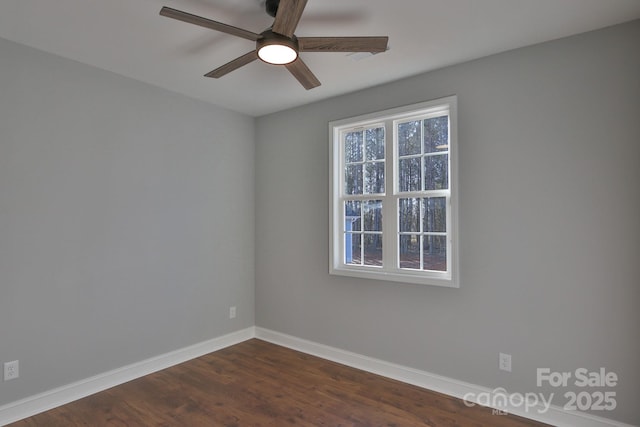 empty room with dark wood-type flooring, baseboards, and a ceiling fan